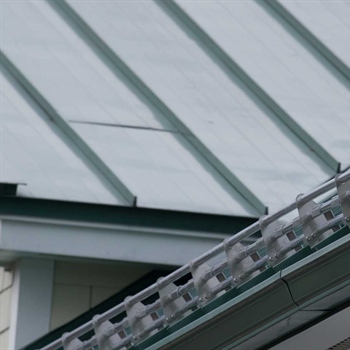Installing AceClamp Metal Roof Snow Bars to prevent roof ice hazards.